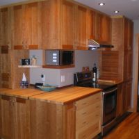 Cuisine en cerisier à l'intérieur comme à l'extérieur. Portes en cerisier massif. Deux modules de tiroirs ont les façades en érable. Le dessus de comptoir est en érable avec un morceau en cerisier au devant. Tout les tiroirs sont en érable avec assemblage à queue d'aronde. Le bois a sa couleur naturelle et est protégé avec une huile. Cuisine en cerisier